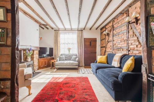 a living room with a blue couch and a brick wall at Sarahs Cottage in Taunton