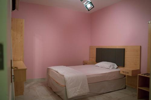 a bedroom with a large bed with pink walls at فردان ريزيدانس - جدة Verdun Residence Jeddah in Obhor