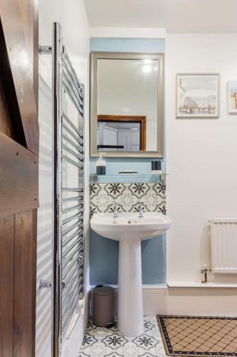a bathroom with a sink and a mirror at Sarahs Cottage in Taunton