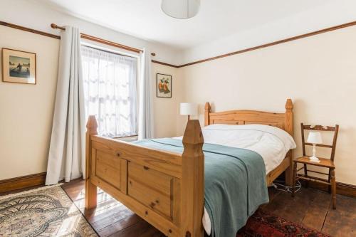 a bedroom with a wooden bed and a window at Sarahs Cottage in Taunton