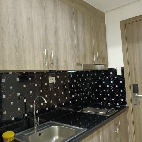 a kitchen with a sink and a black counter top at 1BR Aesthetic Condotel with Balcony - EDSA in Manila