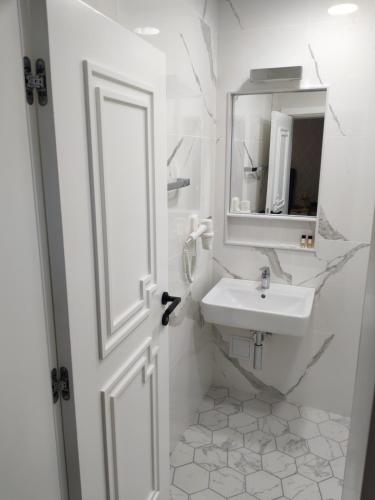a white bathroom with a sink and a mirror at Luxury rooms 12-2 in Plovdiv