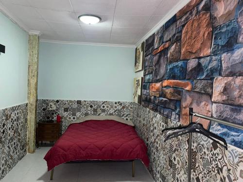 um quarto com uma cama vermelha contra uma parede de pedra em Amplia habitación céntrica em Cartagena