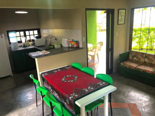 a kitchen with a table with green chairs and a counter top at Chalé Verde in Tamandaré