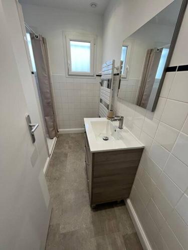 une salle de bain avec un lavabo et un miroir dans l'établissement T2 Etelria les pieds dans l'eau, à Plouhinec