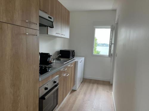 une cuisine avec un évier et une cuisinière four supérieur dans l'établissement T2 Etelria les pieds dans l'eau, à Plouhinec