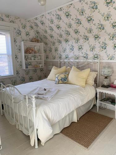1 dormitorio con cama blanca y papel pintado con motivos florales en Foxingham Farm Bed & Breakfast, en Mulmur