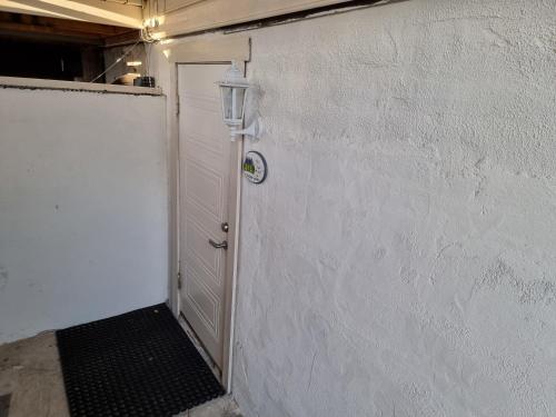 a white door with a light on the side of a building at Kjellerleilighet egen inngang. in Stange