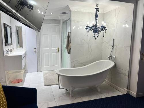 a white bathroom with a tub and a chandelier at Apartment on 32 in Cape Town