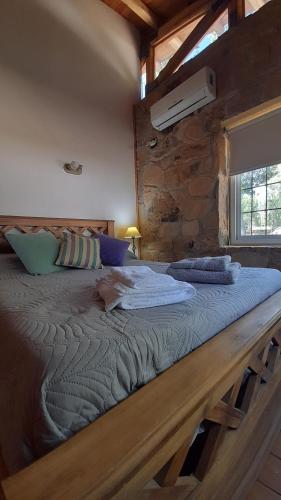 uma cama grande num quarto com uma parede de pedra em Cabaña Quinta La Gringa, San Rafael em São Rafael