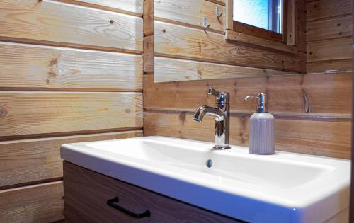 ルカにあるRukan Talvihovitの白い洗面台と木製の壁が備わるバスルーム