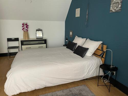 ein Schlafzimmer mit einem weißen Bett und einer blauen Wand in der Unterkunft Duplex tout confort Menen in Menen