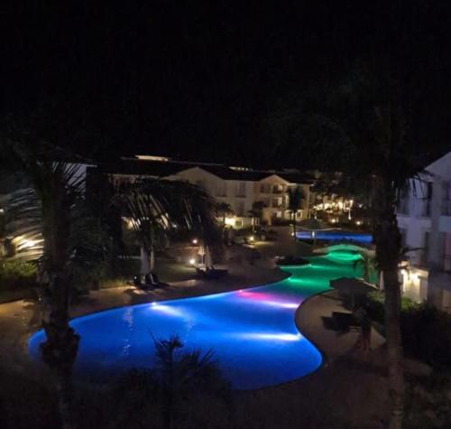 a swimming pool at night with blue and green lights at Hotel Palmera Bayahibe in Bayahibe