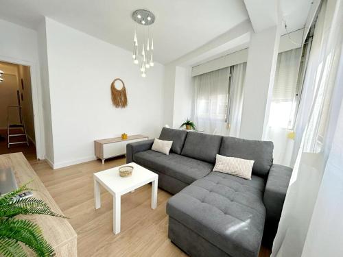 een woonkamer met een grijze bank en een tafel bij Maravilloso apartamento en el centro in Ceuta