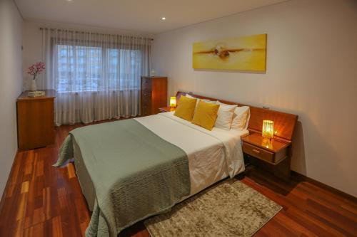 een slaapkamer met een bed met gele kussens en een raam bij Aromas Flavors Tours Esmoriz Beach in Esmoriz