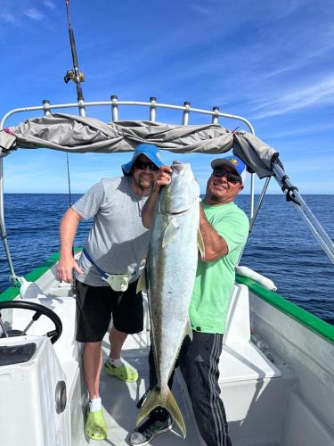 two men on a boat holding a large fish at Casa rodante los cachorones in Loreto