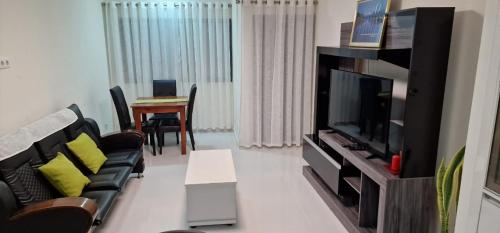 Una sala de estar con un sofá y un televisor. en SUITES-HOME, CIDADELA, en Praia