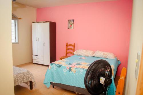 - une chambre avec un lit et un mur rose dans l'établissement Brisa do Mar Hotel, à Arroio do Sal