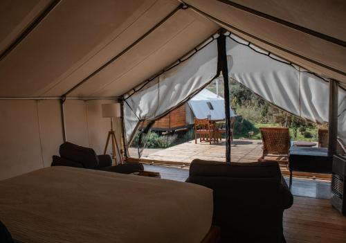 a tent with a bed and chairs and a patio at Hotel Cuatro Cuatros in Ensenada