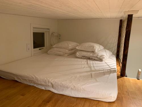 a bed with white sheets and pillows in a room at Fullt utrustat Minihus på landet in Västerhaninge