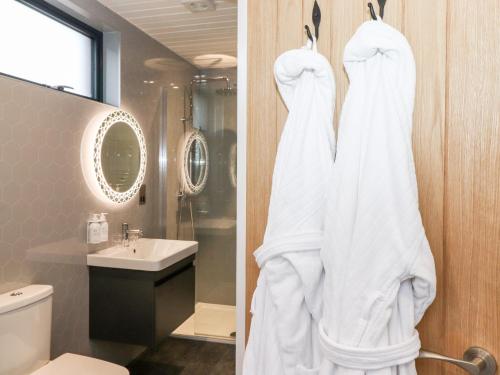 a bathroom with a shower and a white robe at Herdwick Cabin in Penrith