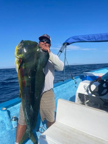 a man holding a large fish on a boat at Casa rodante los cachorones in Loreto