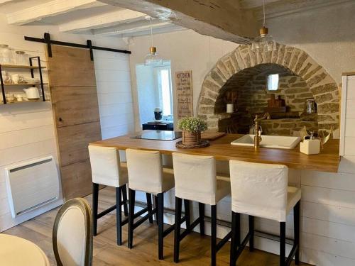 une cuisine avec un bar avec des chaises blanches et un évier dans l'établissement L'écrin, charmant cottage aux portes de la cité médiévale de Semur-en-Auxois, à Chevigny