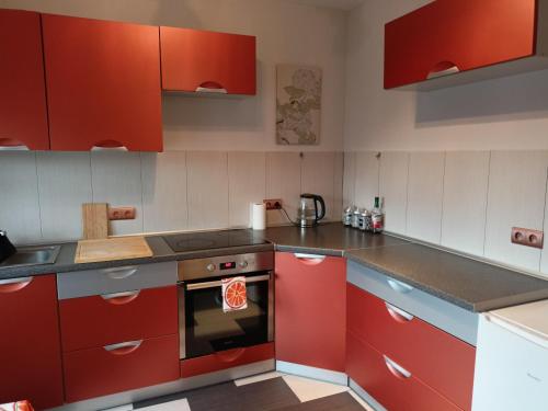 a kitchen with red cabinets and a stove top oven at Lemuria Przytulny pokój Chojnowska in Legnica