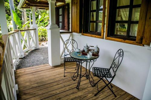 un patio con mesa y sillas en un porche en Monte Sagrado Reserve-100 acres Wellness River cabin, en Quebrada