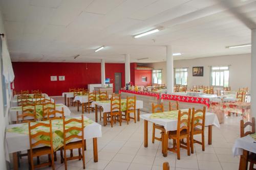 a dining room with tables and chairs and red walls at Brisa do Mar Hotel in Arroio do Sal