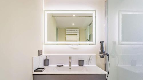 bagno bianco con lavandino e specchio di Le SAPHIR - Confort - Proche Mag Outlet Troyes - Parking gratuit a Pont-Sainte-Marie