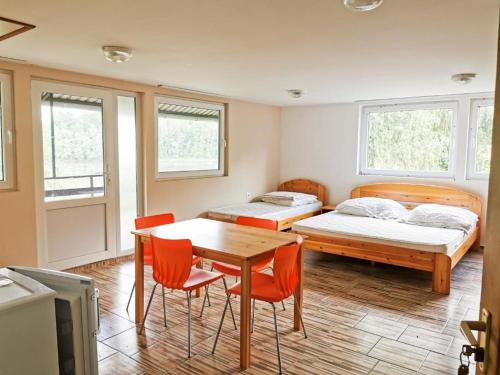 Cette chambre comprend deux lits, une table et des chaises. dans l'établissement Köröstorok Apartmanok, à Csongrád