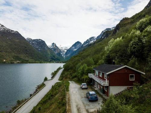 a house with two cars parked next to a lake at Lake View Apartment, Oldedalen in Stryn