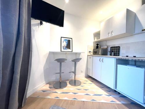 - une cuisine avec des placards blancs et des tabourets dans une pièce dans l'établissement Dans le triangle d’Or de Boulogne, à Boulogne-Billancourt