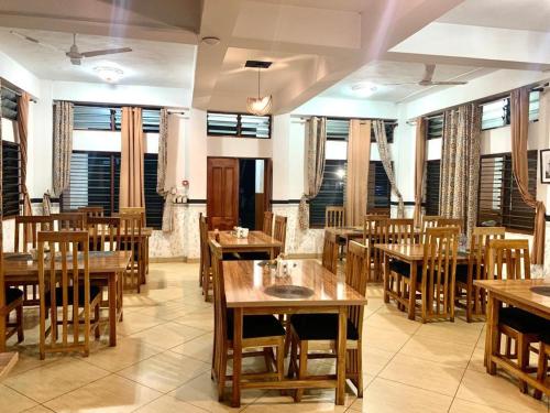 un restaurant avec des tables et des chaises en bois ainsi que des fenêtres dans l'établissement Freeman Methodist Guest House, 
