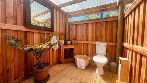 a bathroom with a toilet in a wooden house at Zen Valley Glamping in Plettenberg Bay