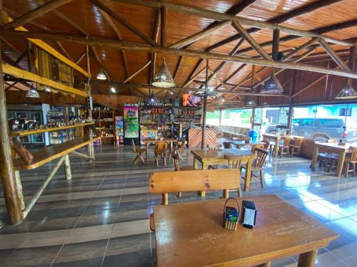 un restaurante con banco de madera, mesas y sillas en Altos da Serra, en São José dos Ausentes