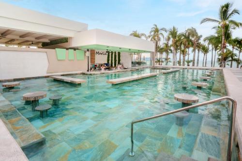 einen Pool in einem Resort mit Palmen in der Unterkunft Riu Palace Pacifico - All Inclusive - Adults Only in Nuevo Vallarta
