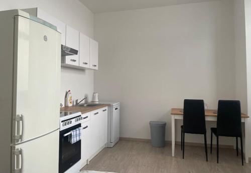 kuchnia z lodówką i stołem z krzesłami w obiekcie Apartman Luksa 