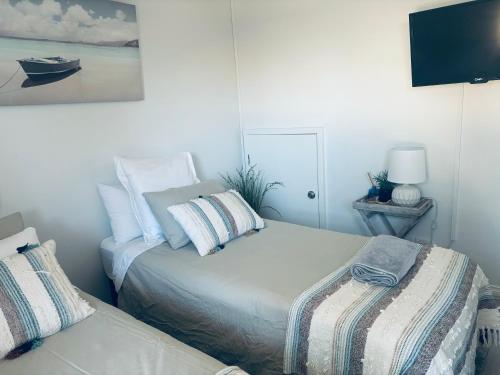 1 Schlafzimmer mit 2 Betten und einem TV an der Wand in der Unterkunft U2 at Moana Beach Esplanade - Exclusive 2 Bdrm Apt - WiFi - Spa - Pet Friendly in Moana