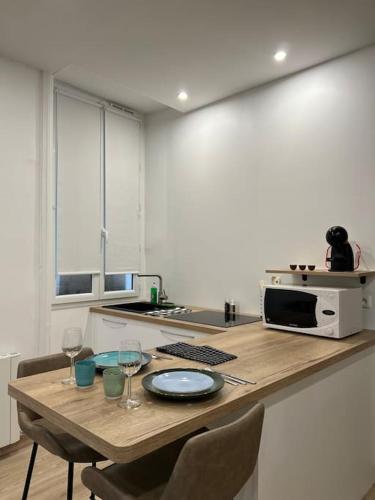 a kitchen with a table with two glasses and a microwave at * Cosy & Netflix Proche Centre * in Nantes