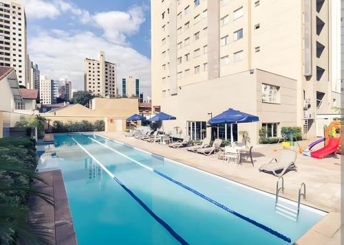 una gran piscina con sillas y sombrillas en un edificio en M-Flat II Hotel - Vila Olimpia en São Paulo