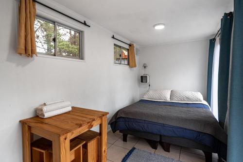 a bedroom with a bed and a wooden table at Cabañitas del Bosque in Algarrobo