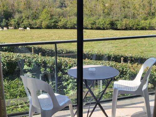 two chairs and a table on a balcony with a field at Logis Le Cadusia in Chaource
