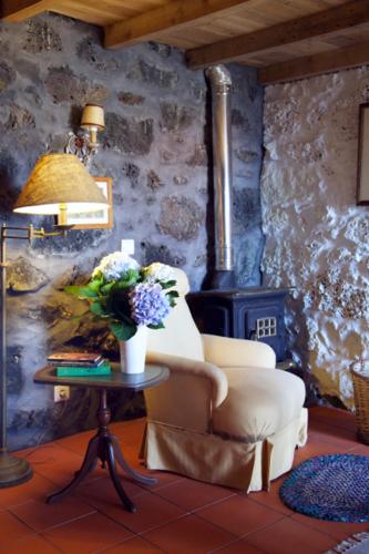 a living room with a chair and a table with flowers at Aldeia das Cagarras in Santo Amaro