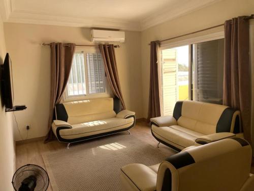 een woonkamer met banken en stoelen en een televisie bij Superbe 2pieces avec climatisation in Fatick
