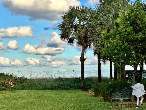 Eine Frau, die auf einer Bank in einem Park mit Palmen sitzt. in der Unterkunft Sapphire by the Sea in Fort Lauderdale