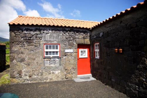 una puerta roja en un edificio de piedra con una puerta roja en Aldeia das Cagarras en Santo Amaro