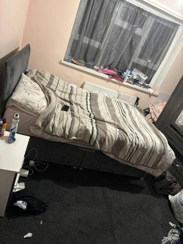 een ongemaakt bed in een kamer met een bureau en een raam bij Spacious flat in Tilehurst
