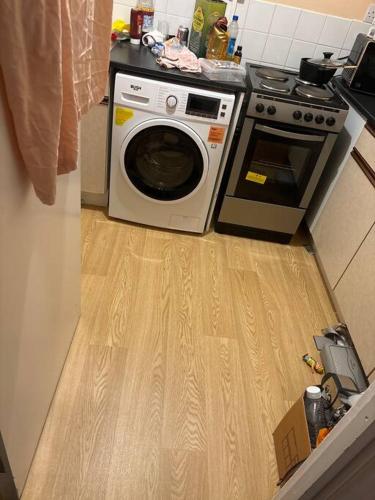 een keuken met een wasmachine op een houten vloer bij Spacious flat in Tilehurst